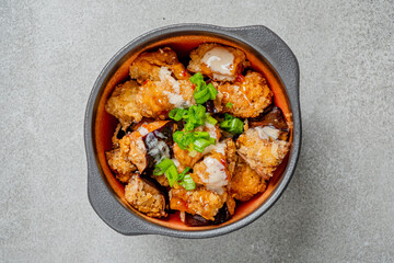 A bowl filled with crispy fried chicken pieces and colorful vegetables, garnished with green onions