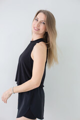 Smiling Woman in Black Casual Outfit Posing Against a Light Background