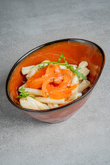 Smoked salmon artfully placed atop creamy pasta, beautifully garnished with fresh herbs in a bowl