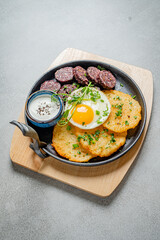 Delicious skillet presents golden potato pancakes, a perfectly cooked egg, and savory sausages