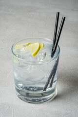A glass filled with ice and a splash of lime sits on a gray table, inviting a moment of refreshment