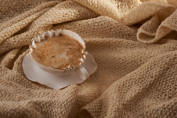 cup of cuppuсcino on beige knitting backgrund
