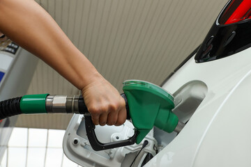 Hand with nozzle refueling a vehicle at a service station