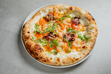 Freshly baked seafood pizza with shrimp, octopus, and arugula served on a rustic plate