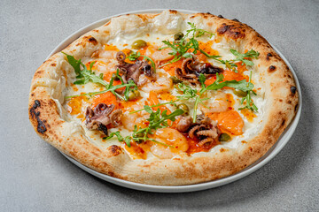 Savor a delicious seafood pizza with shrimp, octopus, and fresh greens in a cozy restaurant