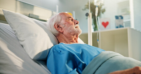 Sleeping, senior man and patient on hospital bed for operation recovery, healing or post surgery. Rest, sick and elderly person in clinic for healthcare, anesthesia and iv drip for medical treatment