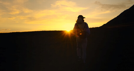 Silhuette Young Woman walking on the mountain observing sunset.