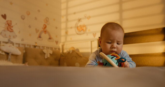 Baby boy following somebody with his eyes while massaging gums with fingers. Toddler salivating while teething in early staging of life.
