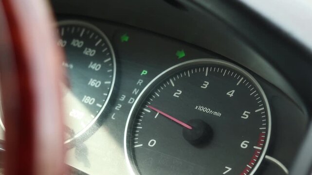 Close up of car dashboard with flashing trafficator lights and the engine revving. Double small illuminated hazard pointer light blinking together.