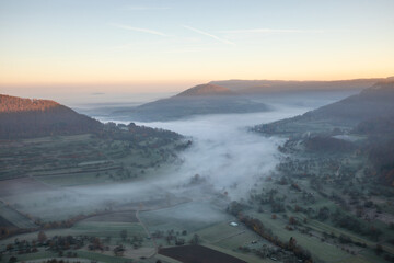 Blick auf das nebelverhangene Neidlinger Tal im Herbst zum Sonnenaufgang, Schwäbische Alb.
