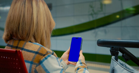 Blonde woman using smartphone, showcasing digital connectivity and mobile technology in urban outdoor setting