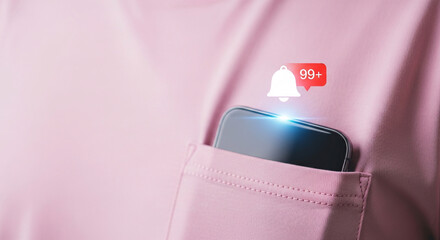 A smartphone in a pink t-shirt pocket with a glowing notification bell icon showing 99+ alerts.