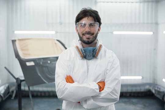 Portrait of an auto body technician in protective gear in a spray booth - Powered by Adobe
