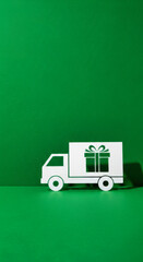 Paper truck delivers gift box against green background, hinting at evergreen holiday deals and high contrast promotion. Represents Christmas sale, Black Friday or general end-of-year savings.