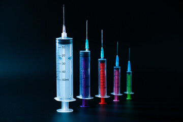 A vibrant lineup of various-sized syringes on a dark background, representing pharmaceutical...