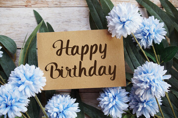 Happy Birthday text with flowers bouquet decoration on wooen background