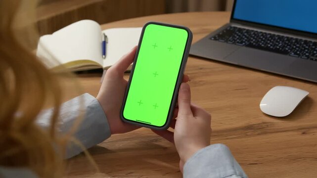 Woman sit use digital tech cell phone open green screen mock up. Hand scroll phone web site swipe unlock. Girl hold mobile closeup. Turn on chroma key page Cozy home background. Online app copy space