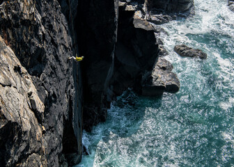 Person rock climbing steep cliff above ocean at Gurnard's Head Cornwall