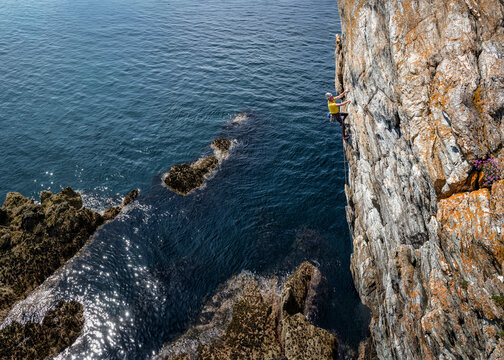 Rock climber scaling sea cliff at Fanfare HVS 4c in Rhoscolyn Wales