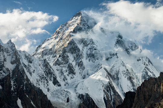 Snow covered K2 mountain peak in Karakorum Pakistan under clouds