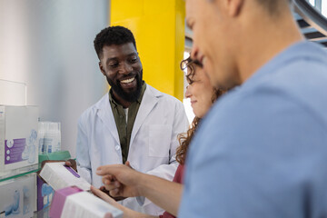 Smiling young pharmacist guiding customers about medicines