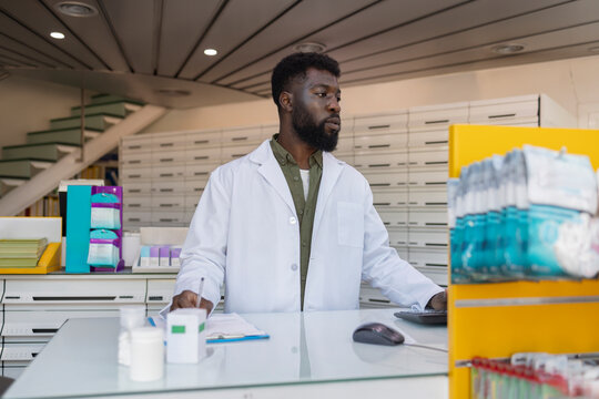Young pharmacist working at desk in pharmacy