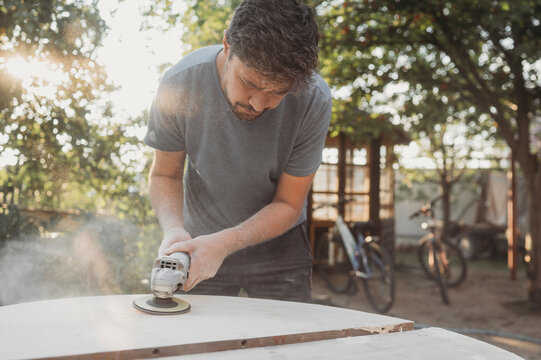 Mature man polishing wooden table in back yard on sunny day
