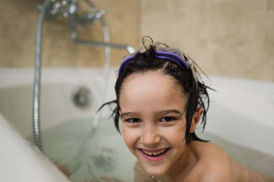 Smiling child bathing in bathtub with goggles in bathroom