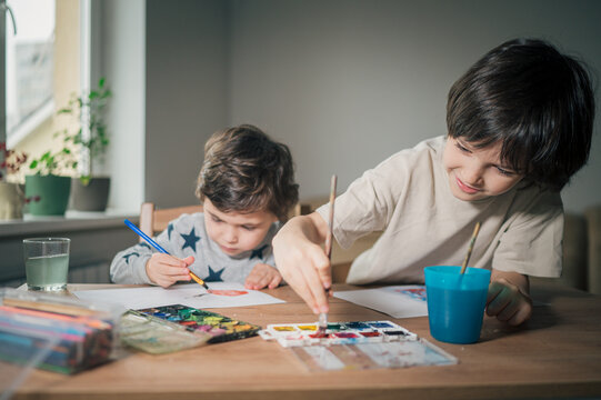 Children drawing and painting together at home with watercolor