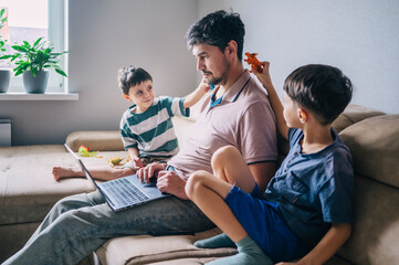 Dad working from home with children playing and learning in living room