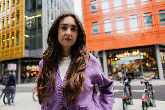 Brunette with purple cardigan in urban city street portrait