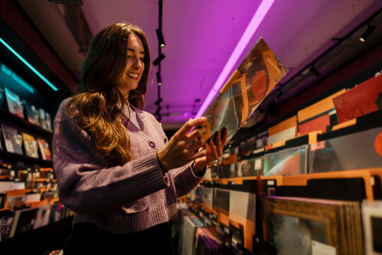 Woman selecting vinyl records in a record store at night
