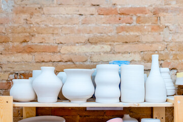 Ceramic pottery art displayed on wooden shelf in pottery class workshop