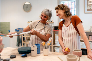 Friends creating ceramic art in a pottery class workshop smiling together