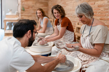 Friends enjoying a pottery class with a teacher in a creative workshop