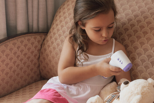 Learning care: child practices health monitoring skills on her bear with a digital thermometer