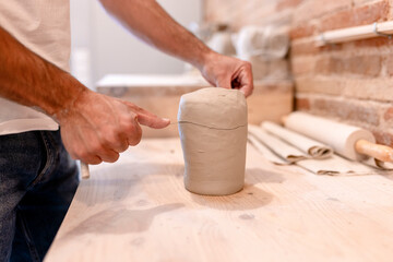 Pottery teacher shaping clay during ceramic art class in workshop