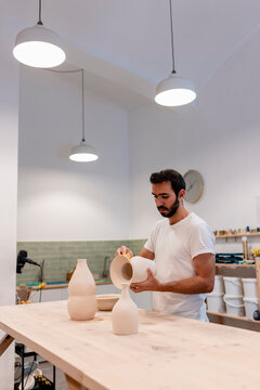 Pottery teacher sculpting ceramic vase at indoor workshop studio