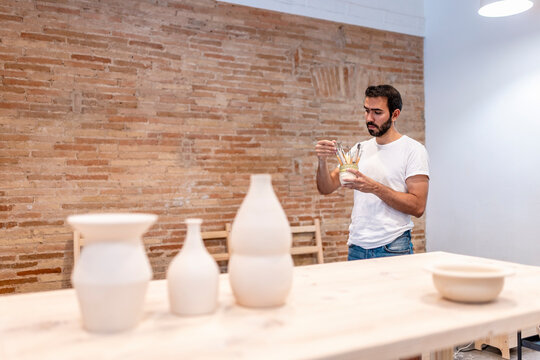 Man teaching pottery class in ceramics art workshop smiling