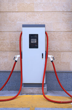 Electric car charging station with red cables outdoors for sustainability