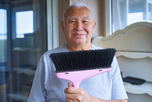 Man holding mop and smiling indoors during housekeeping