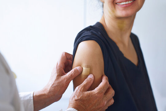 Doctor applying adhesive bandage after vaccination in hospital
