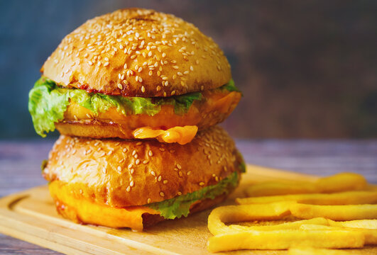 Double cheeseburger with French fries on wooden board