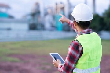 Male engineer checking factory production performance using a tablet, reflecting digital transformation and precision in industrial engineering.