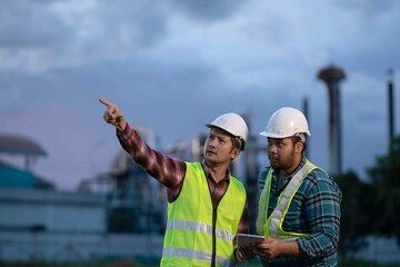 Engineer explaining site layout to colleague while using tablet, symbolizing teamwork, safety, and smart industry practices in construction zones.