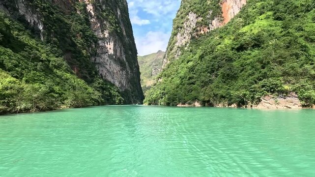 The Nho Que River flows between steep karst mountains in Ha Giang, Vietnam. Turquoise water, narrow canyon walls, and dramatic scenery create a stunning and immersive travel footage.