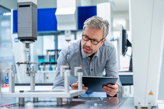 Engineer with tablet inspecting machinery in industrial laboratory
