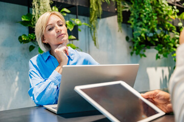 Thoughtful individual working in a modern office with laptop and tablet