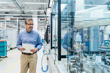 Engineer with tablet inspecting automation machinery in factory