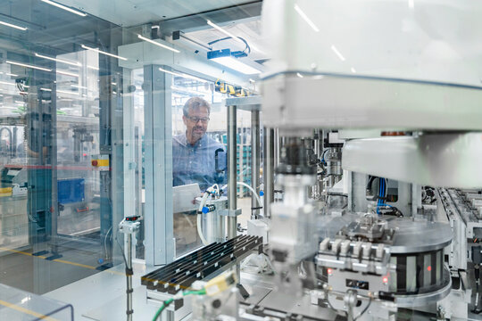 Engineer in automated factory standing by machinery and robots